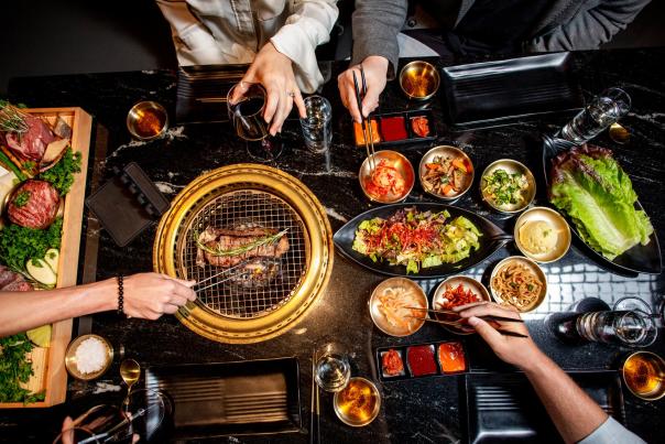 table spread full of food at Zaya 1943 Korean Steakhouse with people eating